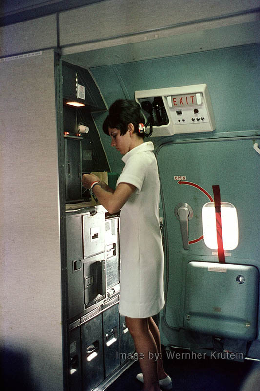 Stewardess at work in galley aboard American Airlines Boeing 727-223 besides the service exit