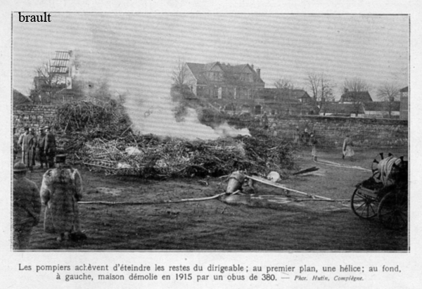 France firefighters around the burning wreckage of Zeppelin LZ86 L39 trying to stop the fire. In the background a house destroyed by a 380mm obus in 1915